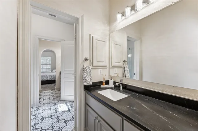 a en suite bathroom with a granite countertop sink and a mirror