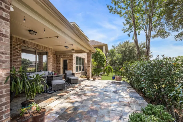 a view of a patio with table and chairs potted plants and floor to ceiling window