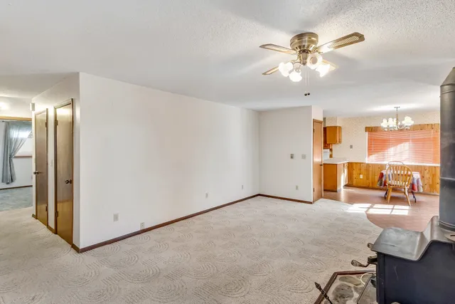 an empty room with chandelier fan and windows