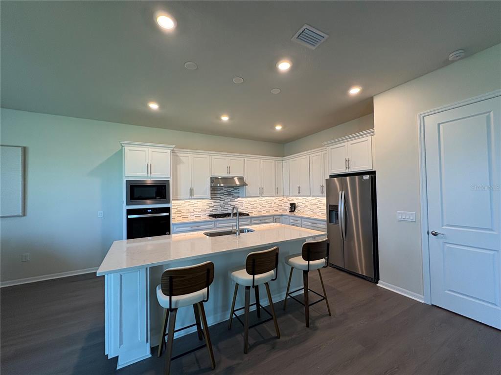 8243 Fenton Street Orlando, FL 32836 - Photo 8 of 35 a kitchen with stainless steel appliances a dining table chairs refrigerator and cabinets