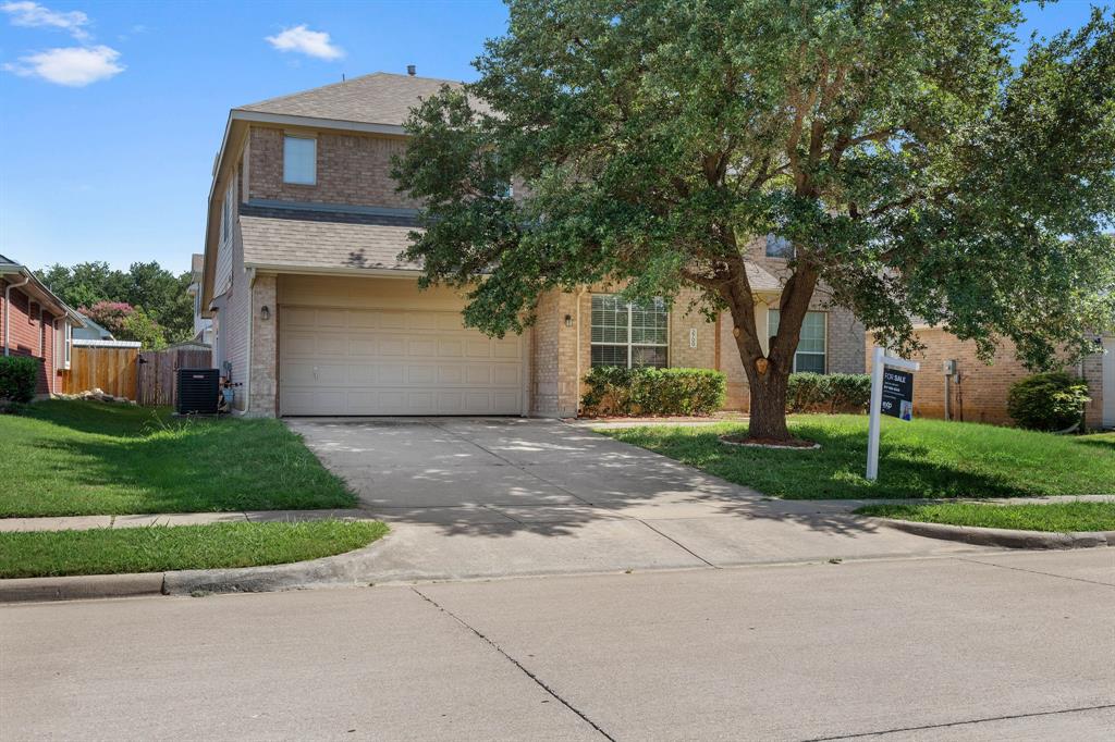 2700 Hereford Road Denton, TX 76210 - Photo 2 of 36 Two-story brick exterior featuring a two-car garage, mature front yard tree, concrete driveway, and established landscaping