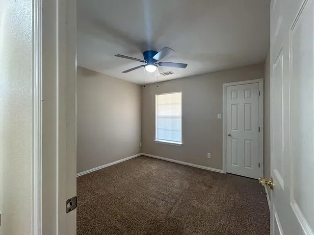 a view of an empty room with a ceiling fan and a window