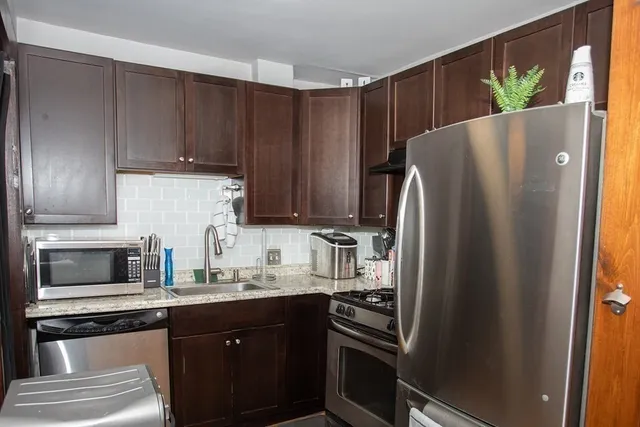 a kitchen with granite countertop a refrigerator stove and sink