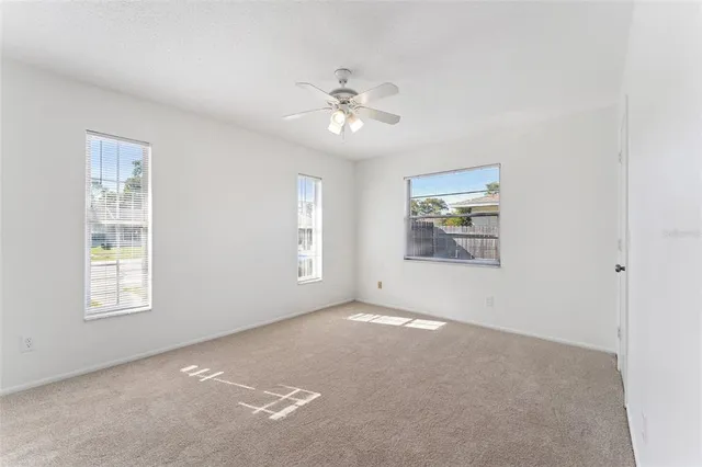 an empty room with windows and fan
