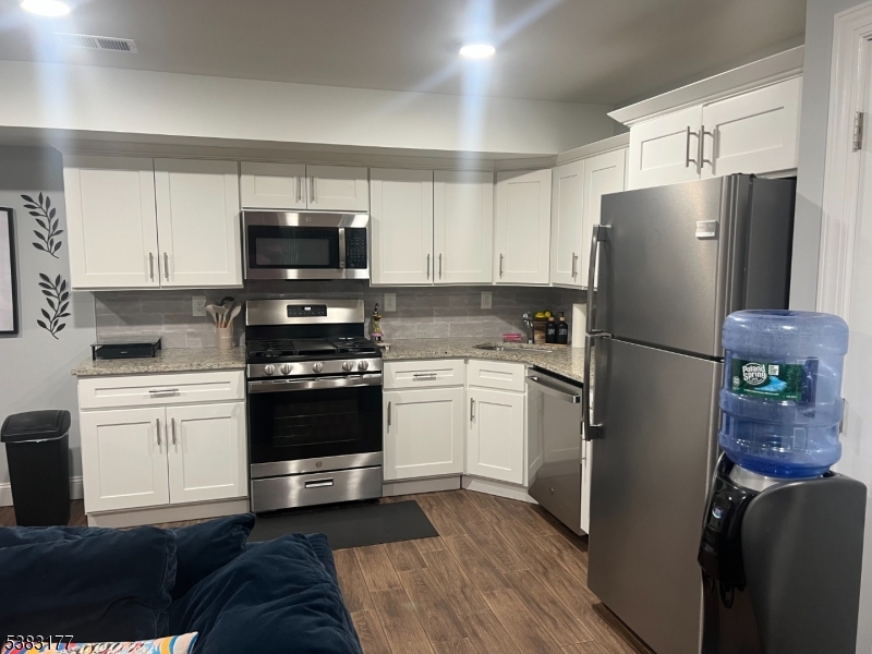 118 Fleming Avenue, Unit 1 Newark, NJ 07105 - Photo 6 of 14 a kitchen with a refrigerator stove and white cabinets