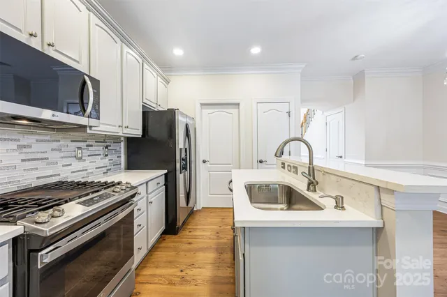 a kitchen with kitchen island stainless steel appliances a sink a stove and cabinets