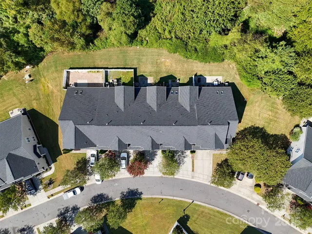 an aerial view of a house with swimming pool and large trees