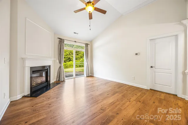 a view of empty room with wooden floor and fireplace