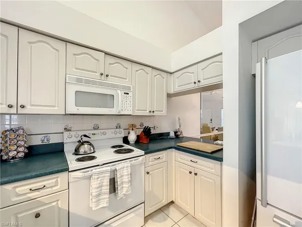 a kitchen with white cabinets and sink
