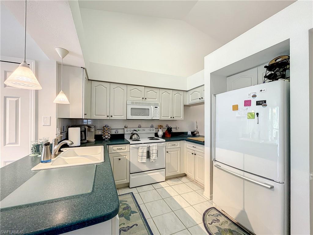 470 Bermuda Cove Way, Unit 2303 Naples, FL 34110 - Photo 27 of 48 a kitchen with stainless steel appliances a refrigerator sink and white cabinets