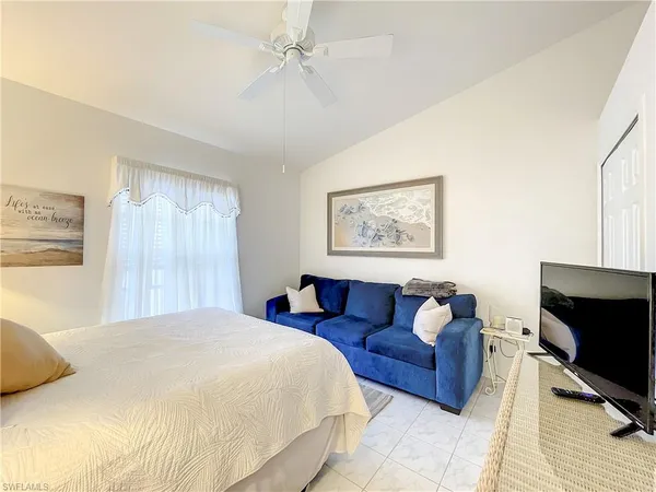 a spacious bedroom with a bed a couch and a flat screen tv