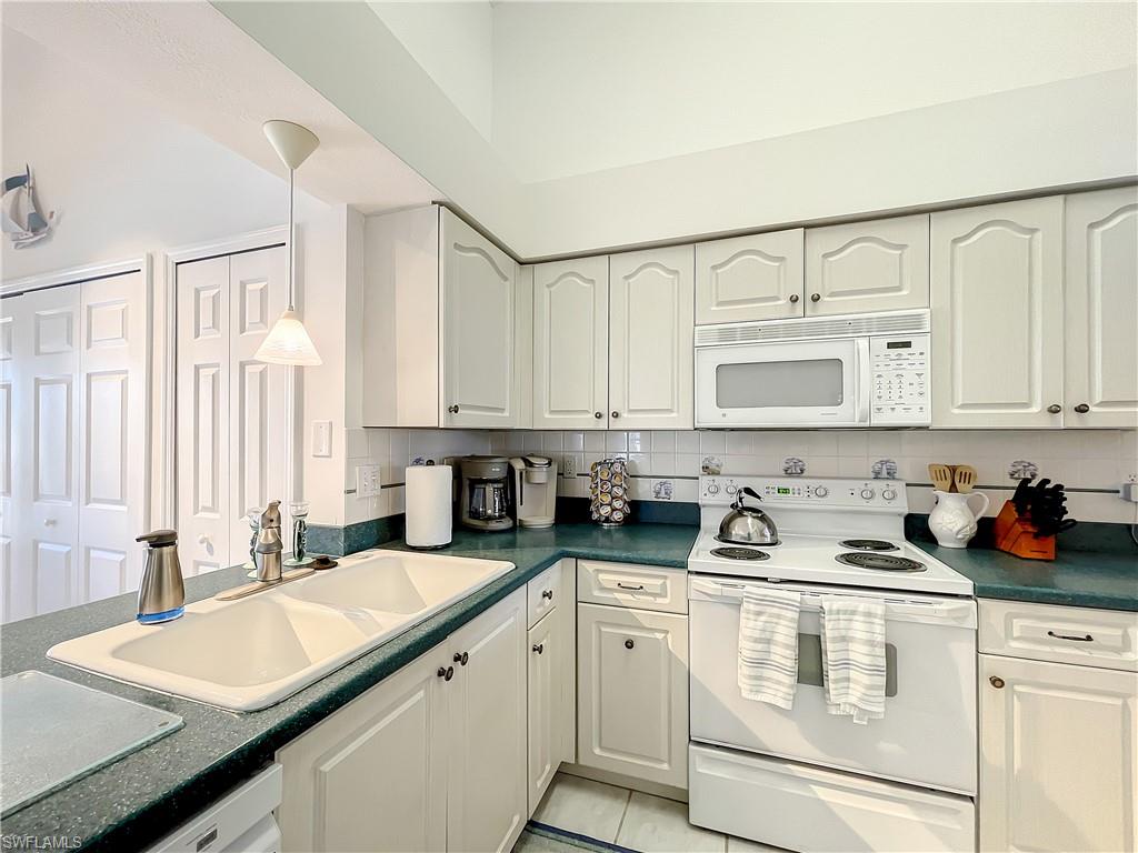 470 Bermuda Cove Way, Unit 2303 Naples, FL 34110 - Photo 46 of 48 a kitchen with stainless steel appliances granite countertop a sink stove and cabinets