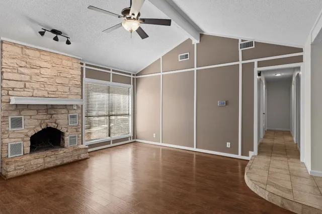 a view of an empty room with wooden floor fireplace and a window