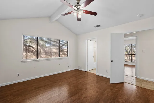 a view of empty room with wooden floor and fan
