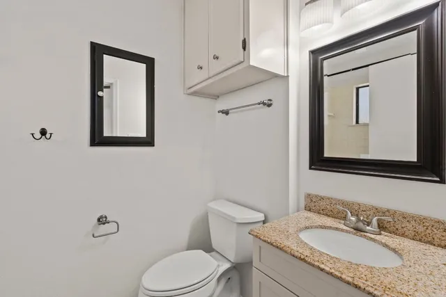 a bathroom with a granite countertop toilet sink and mirror