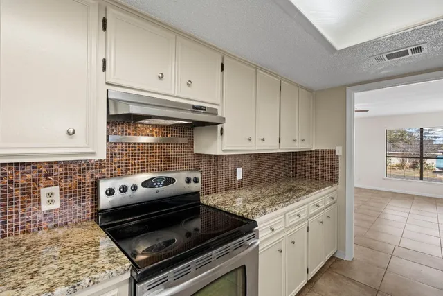 a kitchen with granite countertop a stove sink and cabinets
