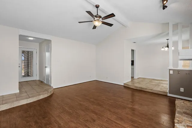a view of an empty room with a ceiling fan and wooden floor