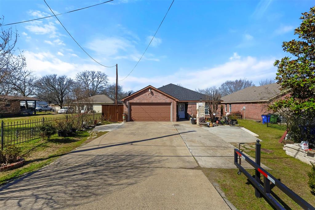 Ranch-style house with brick siding, an attached garage, a front lawn, fence, and driveway