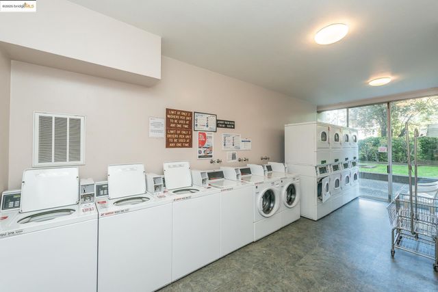 a white kitchen with stainless steel appliances a white table and a large window