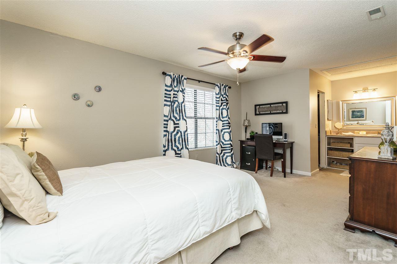 7634 Falcon Rest Circle, Unit 7634 Raleigh, NC 27615 - Photo 16 of 25 a spacious bedroom with a bed and a chandelier