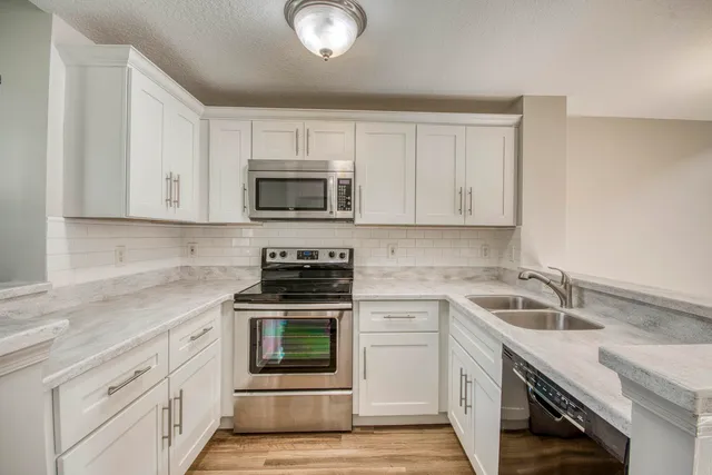 a kitchen with stainless steel appliances a stove sink microwave and cabinets