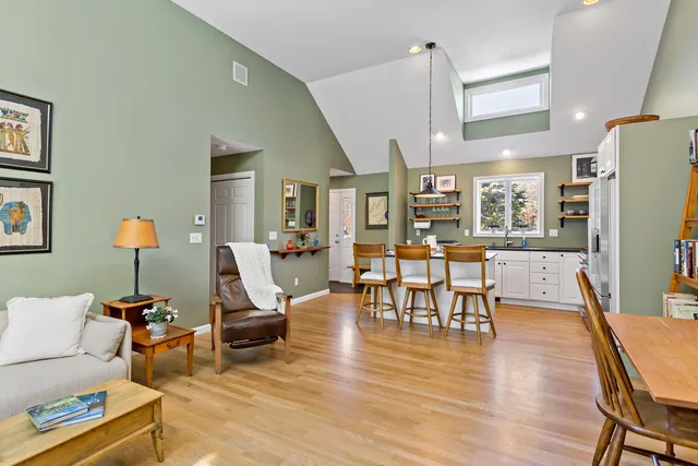 a living room with furniture a table and kitchen view with wooden floor