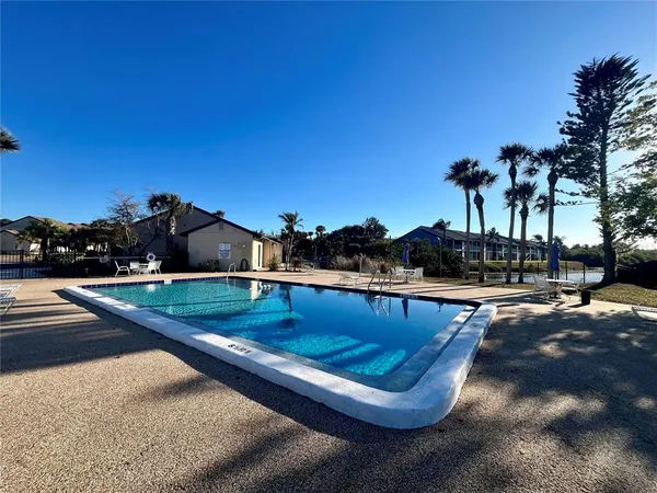 a view of swimming pool with outdoor seating and trees in the background