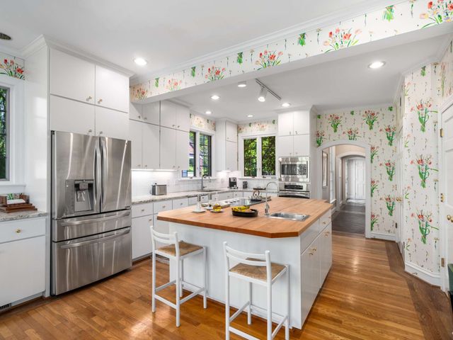 a kitchen with stainless steel appliances granite countertop a refrigerator a sink dishwasher and a refrigerator with wooden floor