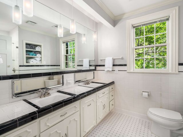 a bathroom with a granite countertop sink a toilet a mirror and a window