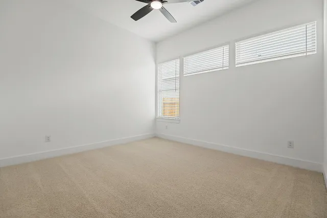 an empty room with a window and a ceiling fan