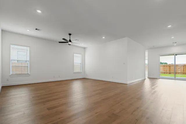 an empty room with wooden floor and windows