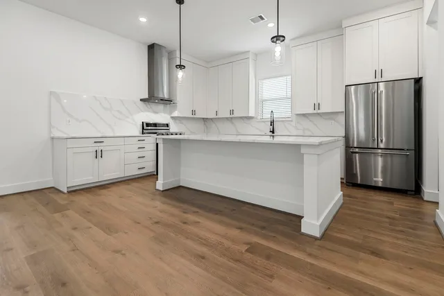 a kitchen with stainless steel appliances granite countertop a sink a stove a refrigerator and island with wooden floor