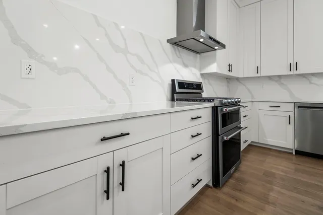 a kitchen with stainless steel appliances a stove a sink and white cabinets