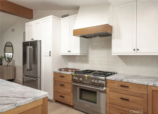 a kitchen with stainless steel appliances granite countertop a sink a stove a refrigerator and chairs