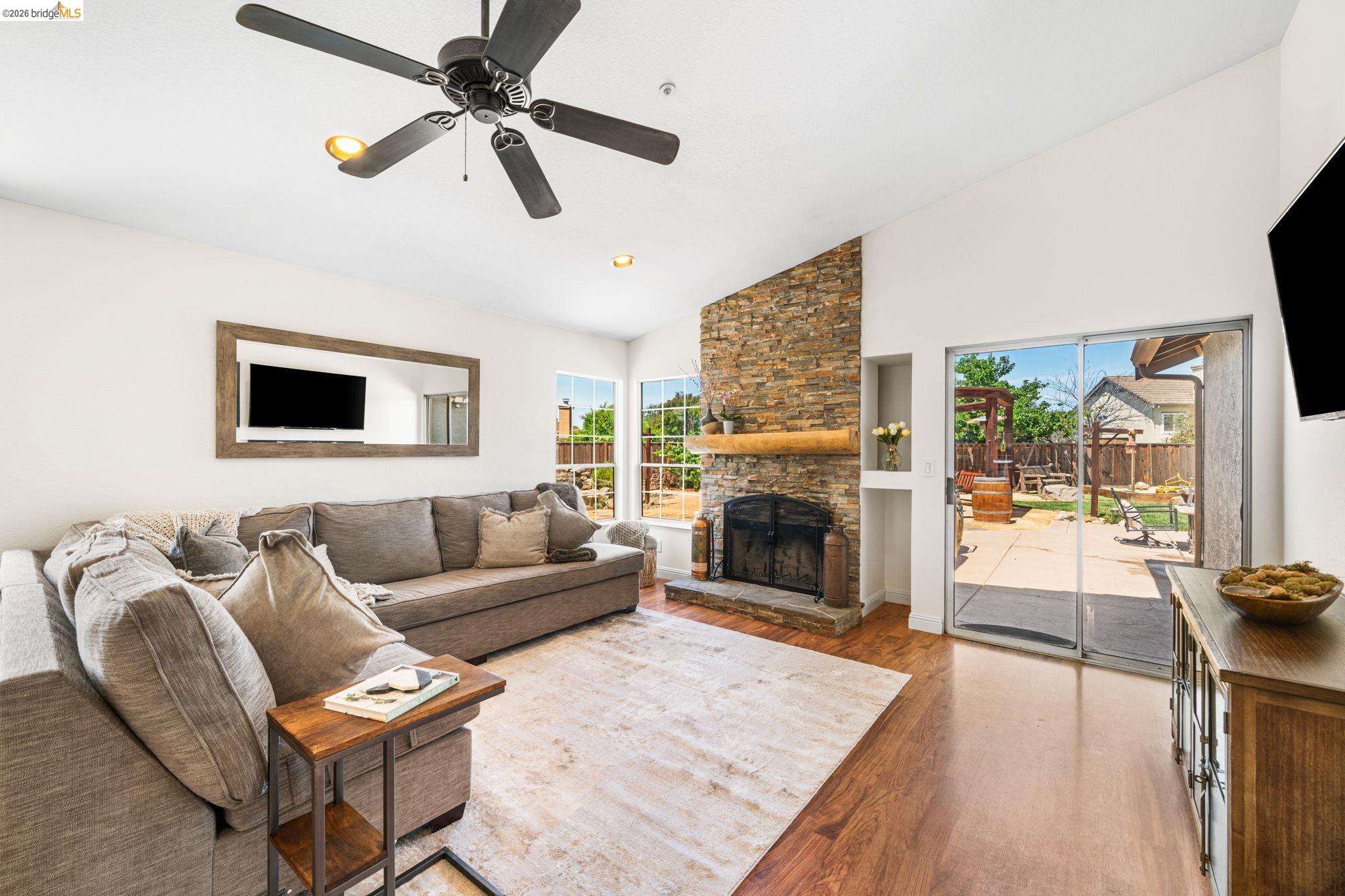 1186 El Rio Court Livermore, CA 94551 - Photo 8 of 60 Spacious living area featuring vaulted ceilings, wood-finish flooring, and a stone fireplace with a substantial wood mantel