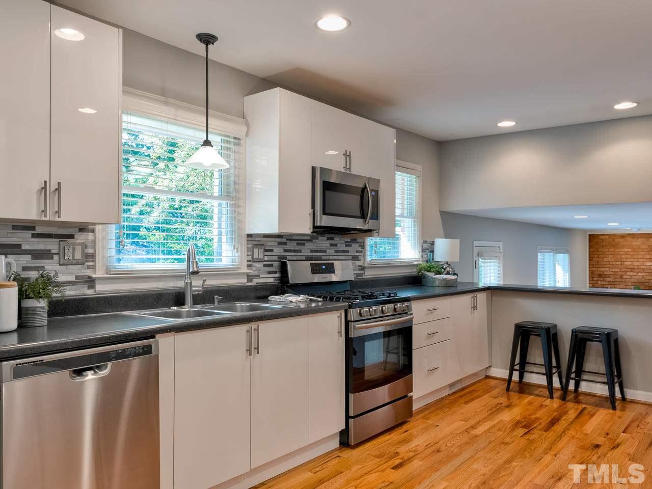 1016 Winona Road Raleigh, NC 27609 - Photo 6 of 25 a kitchen with stainless steel appliances granite countertop a sink a stove a microwave a center island and cabinets