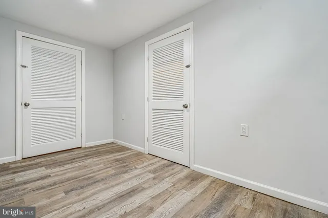 an empty room with wooden floor closet and windows