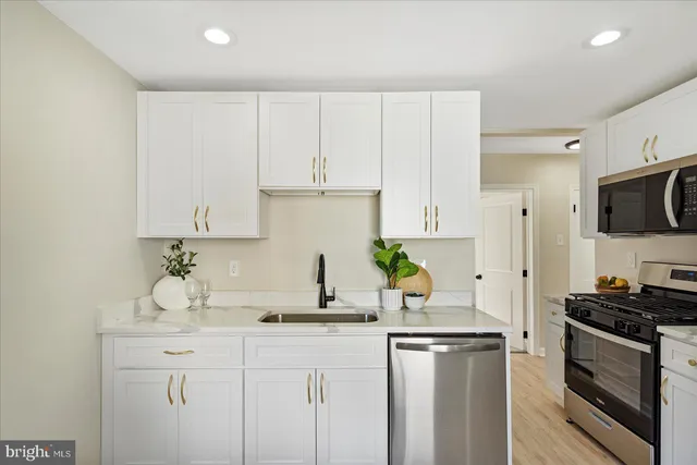 a kitchen with kitchen island granite countertop white cabinets and stainless steel appliances