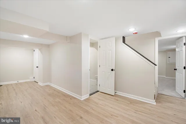 a view of an empty room with wooden floor and stairs