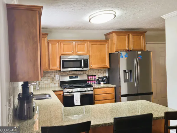 a kitchen with stainless steel appliances granite countertop a refrigerator a stove top oven a sink and dishwasher