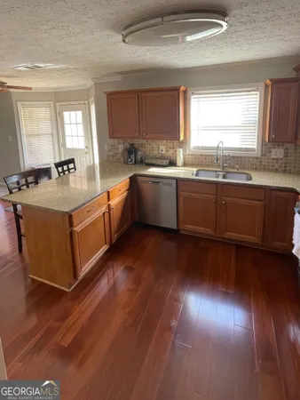 a large kitchen with granite countertop a stove top oven a sink and dishwasher with wooden floor
