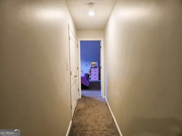 a view of a hallway with wooden floor and a bathroom