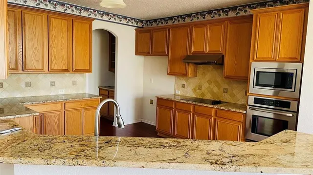 a kitchen with stainless steel appliances granite countertop a refrigerator sink and stove