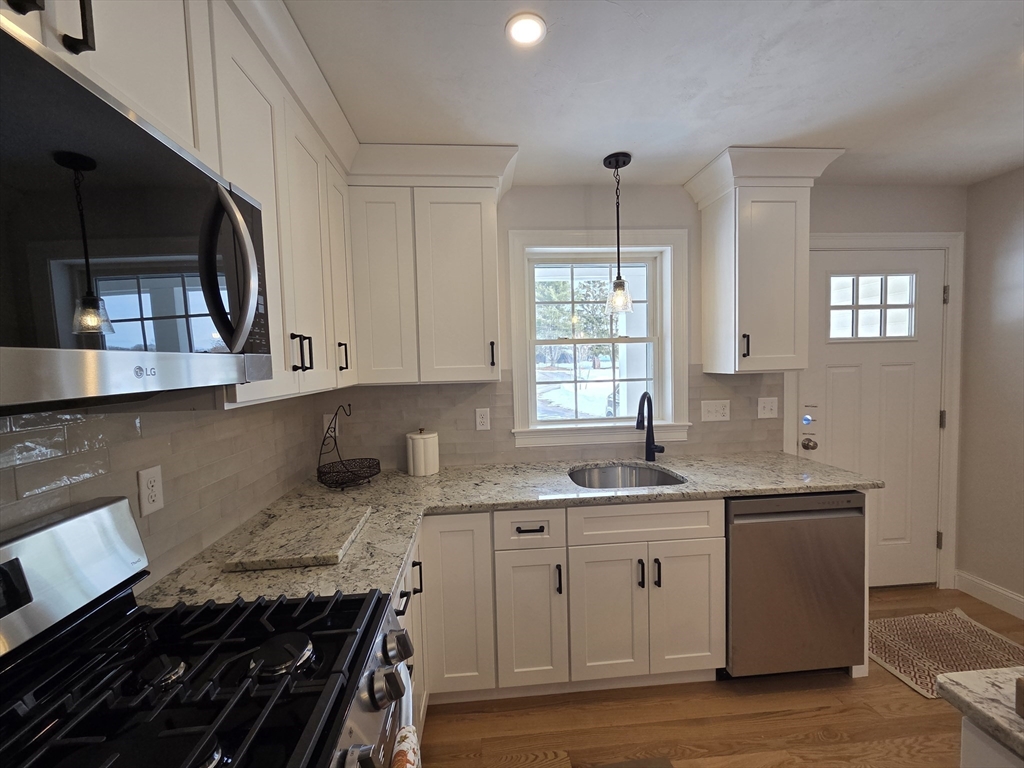 519 Mendon Road, Unit 519 Attleboro, MA 02703 - Photo 5 of 22 a kitchen with granite countertop a sink stove and cabinets