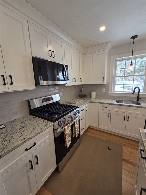 519 Mendon Road, Unit 519 Attleboro, MA 02703 - Photo 6 of 22 a white kitchen with granite countertop a sink a stove and cabinets