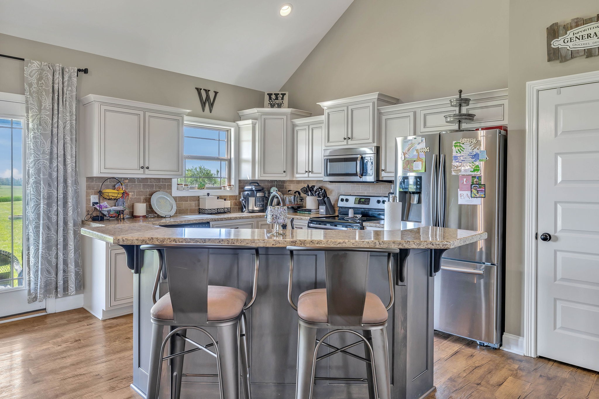 8087 Dunn Road Cedar Hill, TN 37032 - Photo 10 of 33 a kitchen with stainless steel appliances granite countertop a table chairs sink refrigerator and cabinets