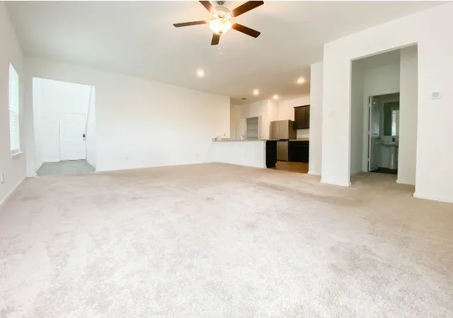 a view of a livingroom with a ceiling fan and kitchen view