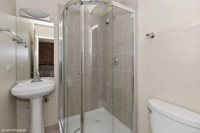 a bathroom with a shower a sink and toilet