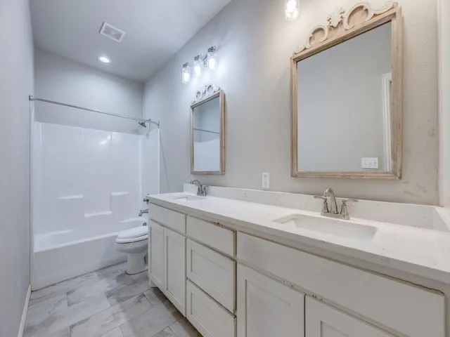 a bathroom with a toilet a sink a mirror a bathtub and vanity