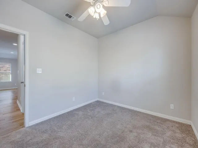 an empty room with a chandelier fan and windows